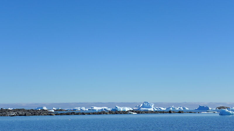 Rocks exposed in the shallow waters near Davis station, with Iceberg Alley behind.