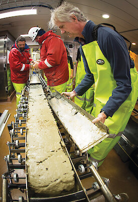 Sediment being removed from a long, rectangular shaped corer.