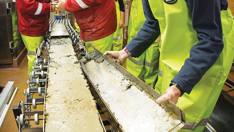 Sediment being removed from a long, rectangular shaped corer.
