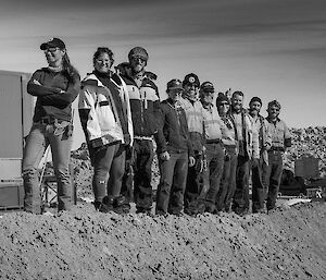 Ten people standing on a pile of dirt in Antarctica.