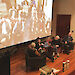 People sitting in conversation on a stage, with a projected image of Antarctic expeditioners behind.