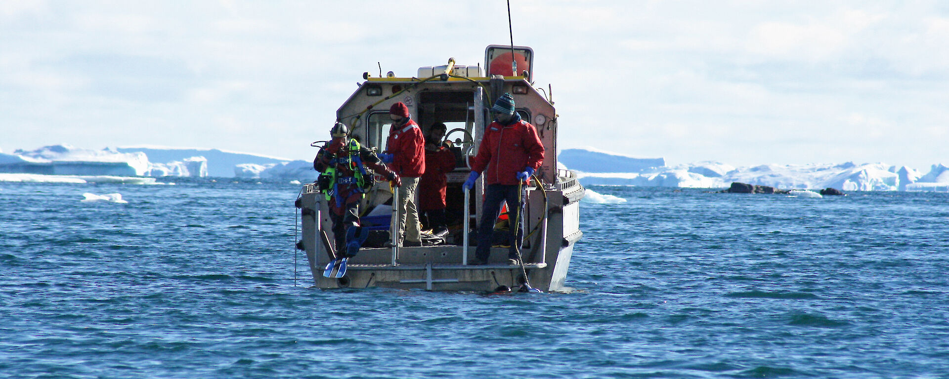 Divers enter the water from a small work boat to conduct an environmental impact assessment in the water near Davis.