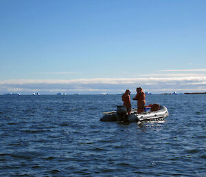 Two scientists in a small boat collecting marine samples.