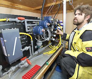 Australian Antarctic Division Science Technical Support technician, Mark Milnes, monitors experimental equipment inside a shipping container in Antarctica.