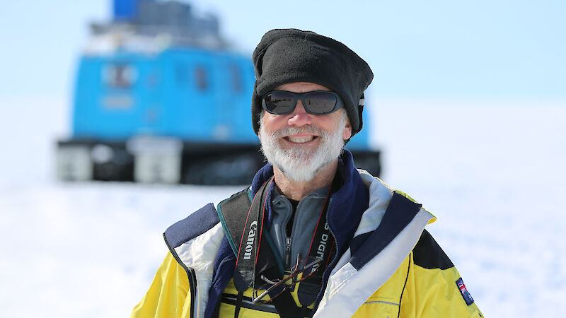 Antarctic Medal recipient Dr John Cadden standing in front of a blue Hagglund in Antarctica.