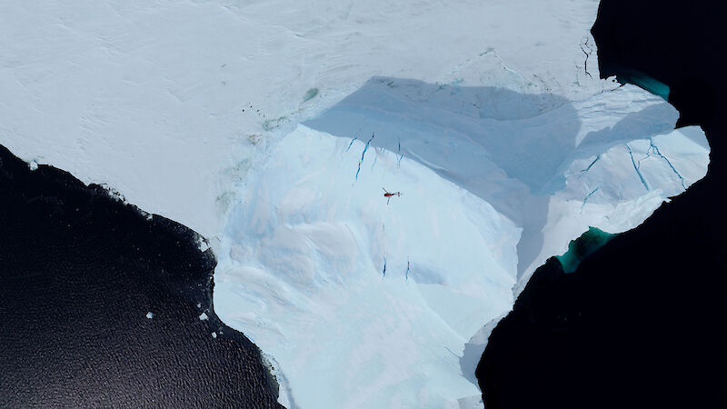 A helicopter flies over an iceberg near Prydz Bay.