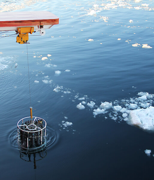 A Conductivity Temperature and Depth (CTD) instrument is lowered over the side of the ship