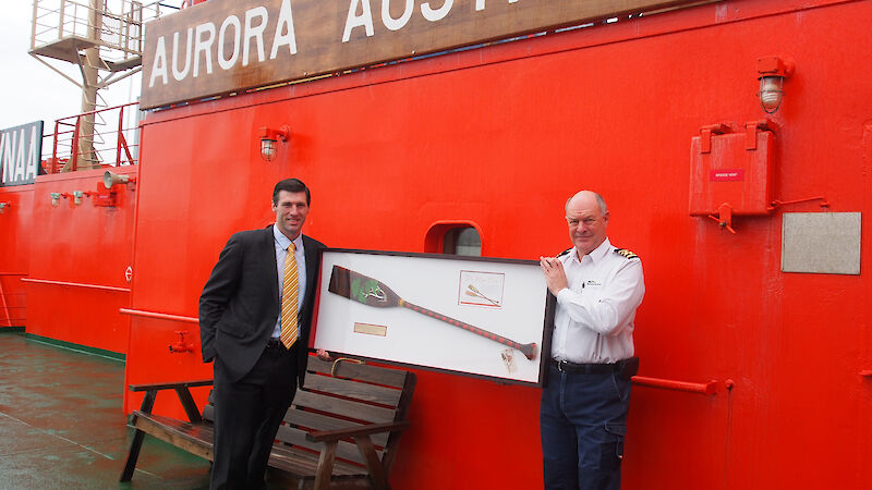 Mr Jason Mundy, General Manager of the Australian Antarctic Division’s Strategies Branch (left) presents the Wiluna paddle to the Master of Aurora Australis, Captain Murray Doyle (right).