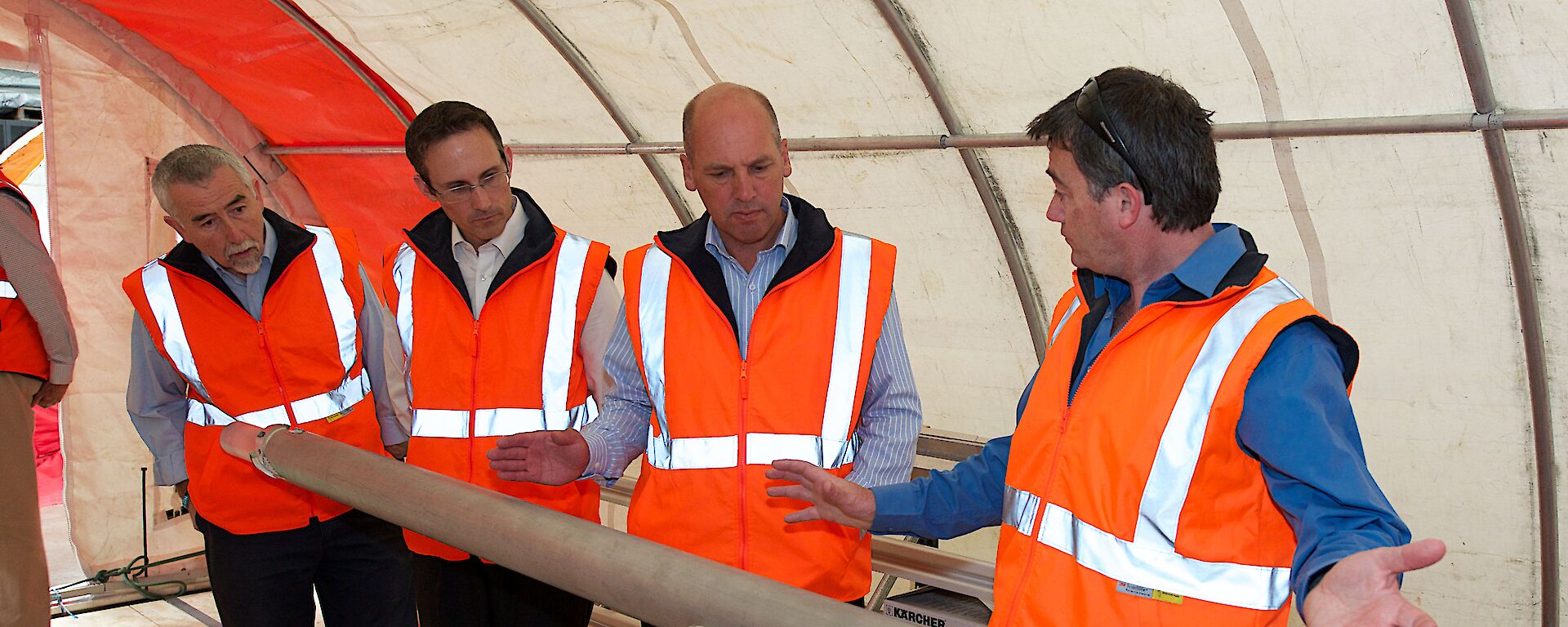 Dr Mark Curran shows the ice core drill to three members of the Senate Standing Committee