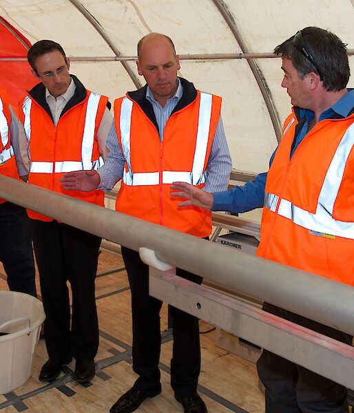 Dr Mark Curran shows the ice core drill to three members of the Senate Standing Committee