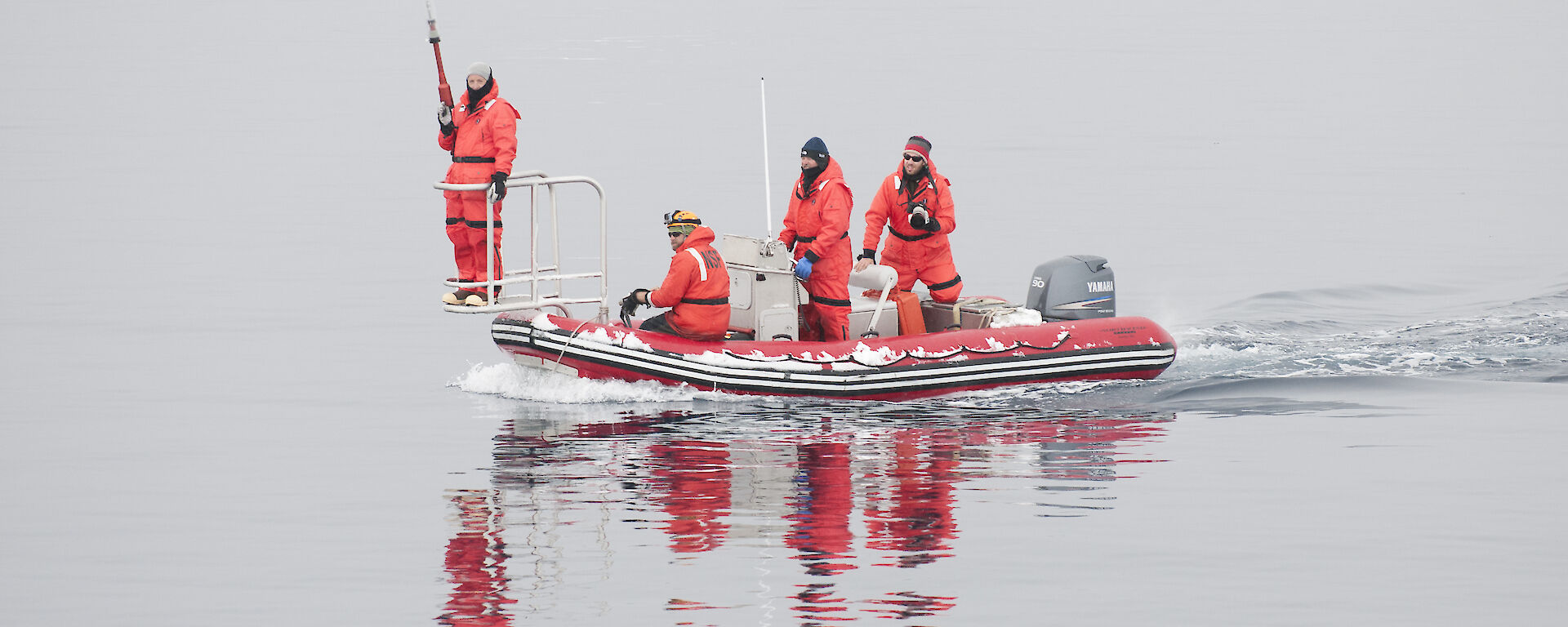 The Australian-American tagging team dressed in red immersion suits in a small boat