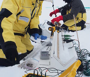 University of Utah mathematics PhD student Christian Sampson measures the electrical conductivity of an ice core. Electrical clamps are attached to nails inserted along the length of the ice core