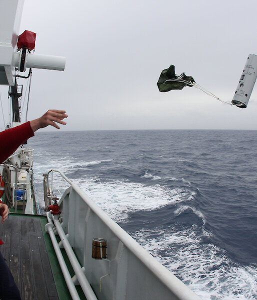 Acoustician Dr Brian Miller throws a sonobuoy into the ocean from the side of the ship