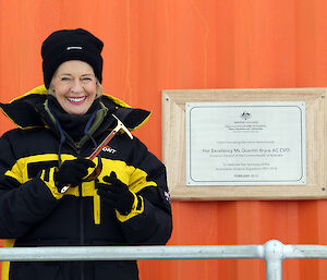 Governor-General Ms Quentin Bryce, dressed in Antarctic clothing, stands beside a plaque commemorating the centenary of Australian Antarctic exploration