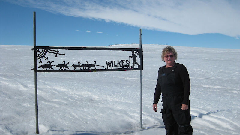 Lyn Maddock standing near a sign in Antarctica