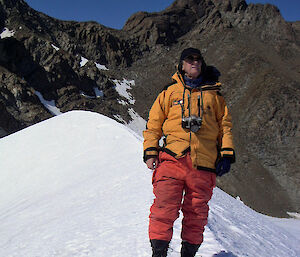 Expeditioner standing on snow with mountain in background