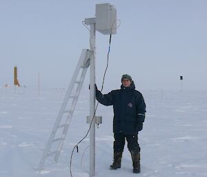 Scientist standing beside an electric field mill at Vostok, Antarctica.