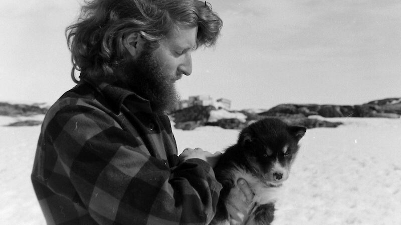 Man with a husky pup during at Wilkes station in 1968