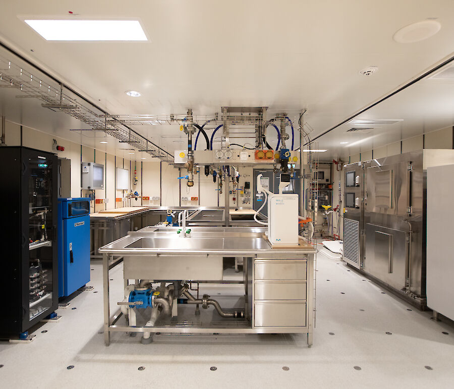 A brightly lit room contains sinks, desks, cabinets and scientific equipment.