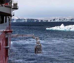CTD rosette hanging from an extended crane boom from the side of a ship in Antarctica.
