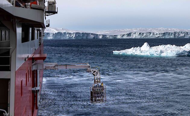 CTD rosette hanging from an extended crane boom from the side of a ship in Antarctica.