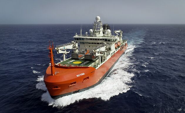 Aerial view of the bow of Nuyina in the Atlantic Ocean, with waves spraying up either side.