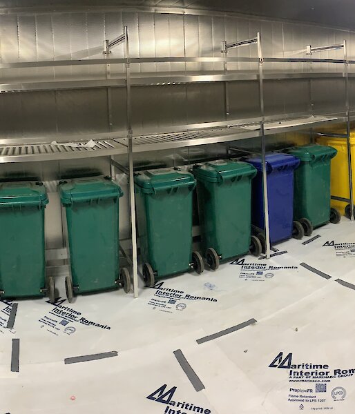 A line of coloured wheelie bins.