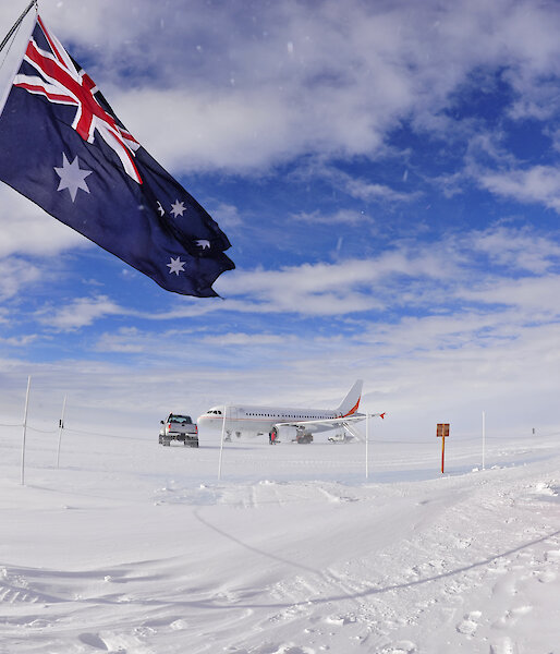 Australian flag flying with aircraft in distance.