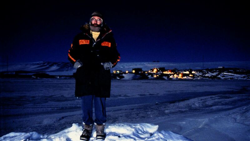 Rugged up man standing on the ice in front of Mawson station