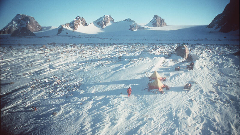 View looking down over field camp of tents in rocky mountains