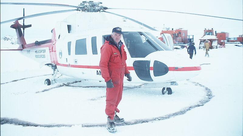 Helicopter pilot standing near parked helicopter