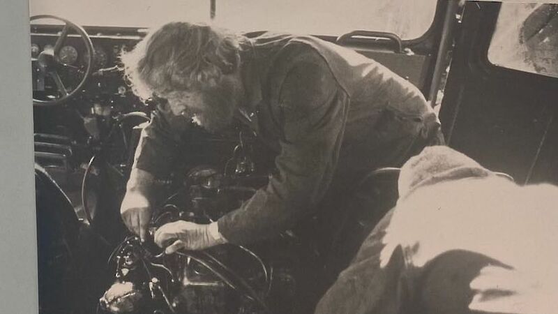Black and white photo of a bearded man working on a vehicle