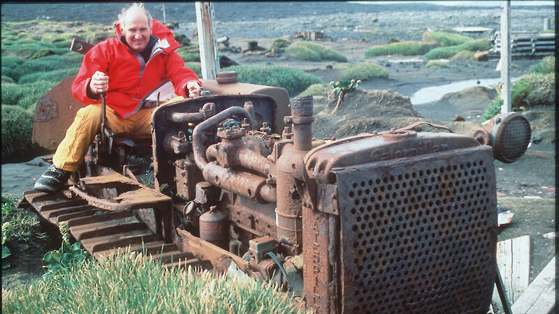 Man sitting on remains of rusting tractor