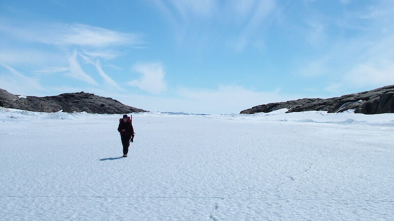 Expeditioner hiking over the ice near coastline