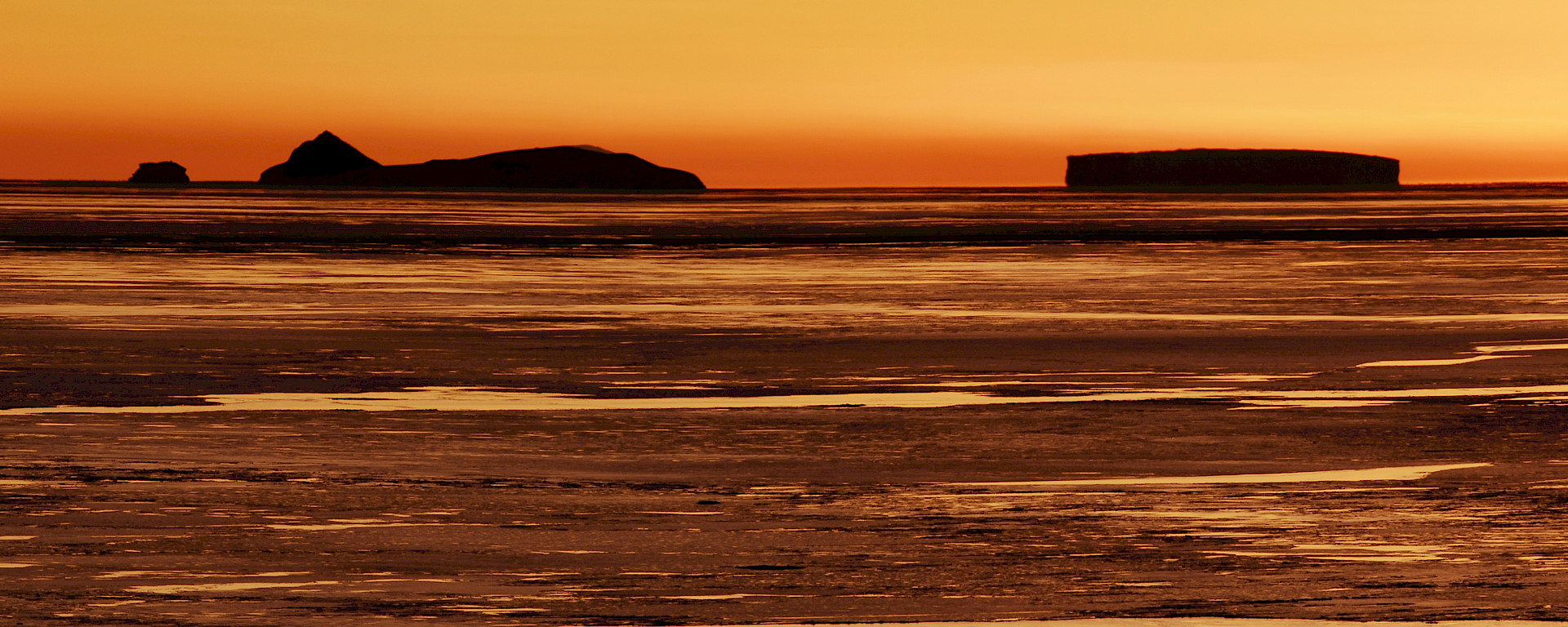 Sunset with the distinctive triangular shaped outline of Nelly Island on horizon