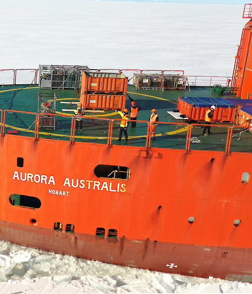 Aerial photograph of an orange icebreaker ship sailing though sea ice.