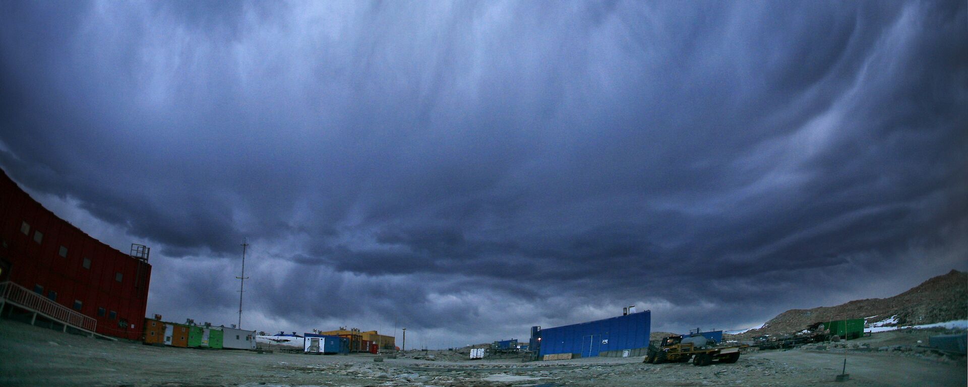 Huge grey and white choulds roll hang low over the red buildings at Casey.