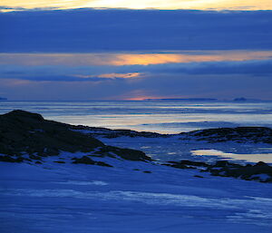 Steely blue water and sky against dark rocky shoreline