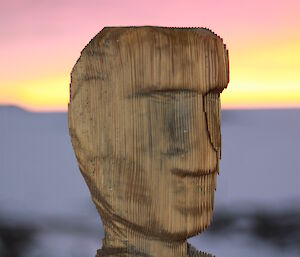 A carved wooden head tops a post in Antarctica.