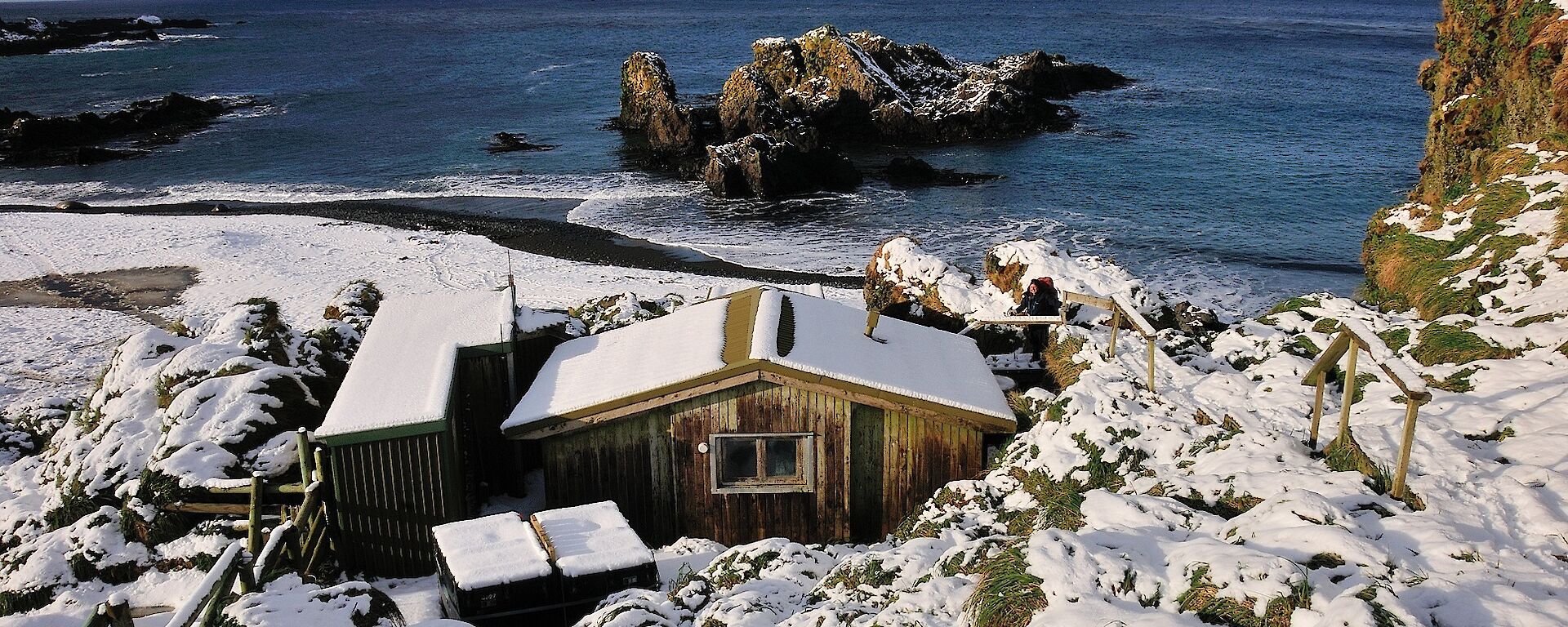 Snowfall over hut building overlooking bay