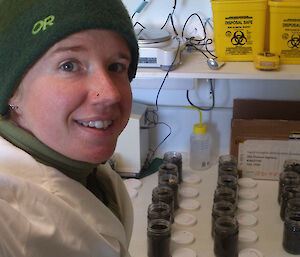 A scientist stands in front of several neatly arranged small soil pots