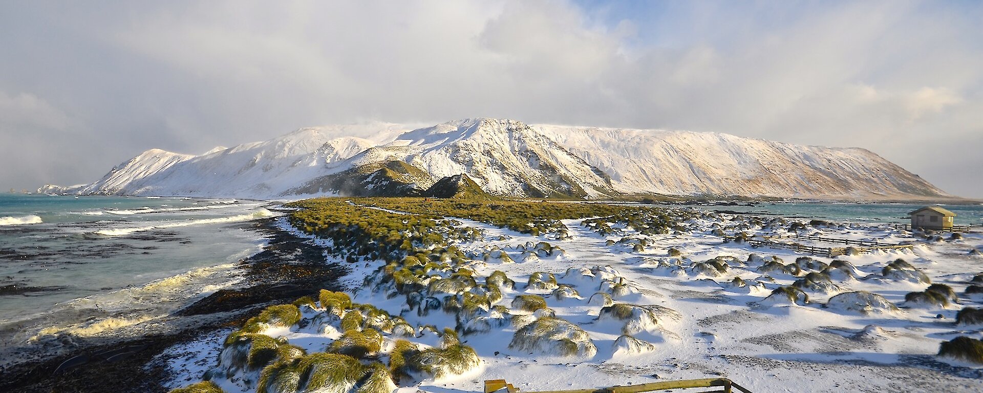 Looking south over the snow covered isthmus and the slopes up to the plateau. In the foreground is a timber fence enclosure to the fuel ‘farm’ including a store area for plastic polypipe and some fencing timber