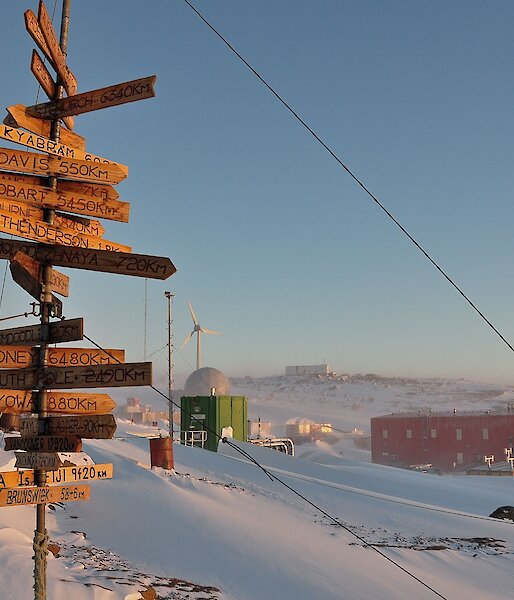 A tall wooden sign featuring many smaller plaques with town names pointing in the direction which they are located.