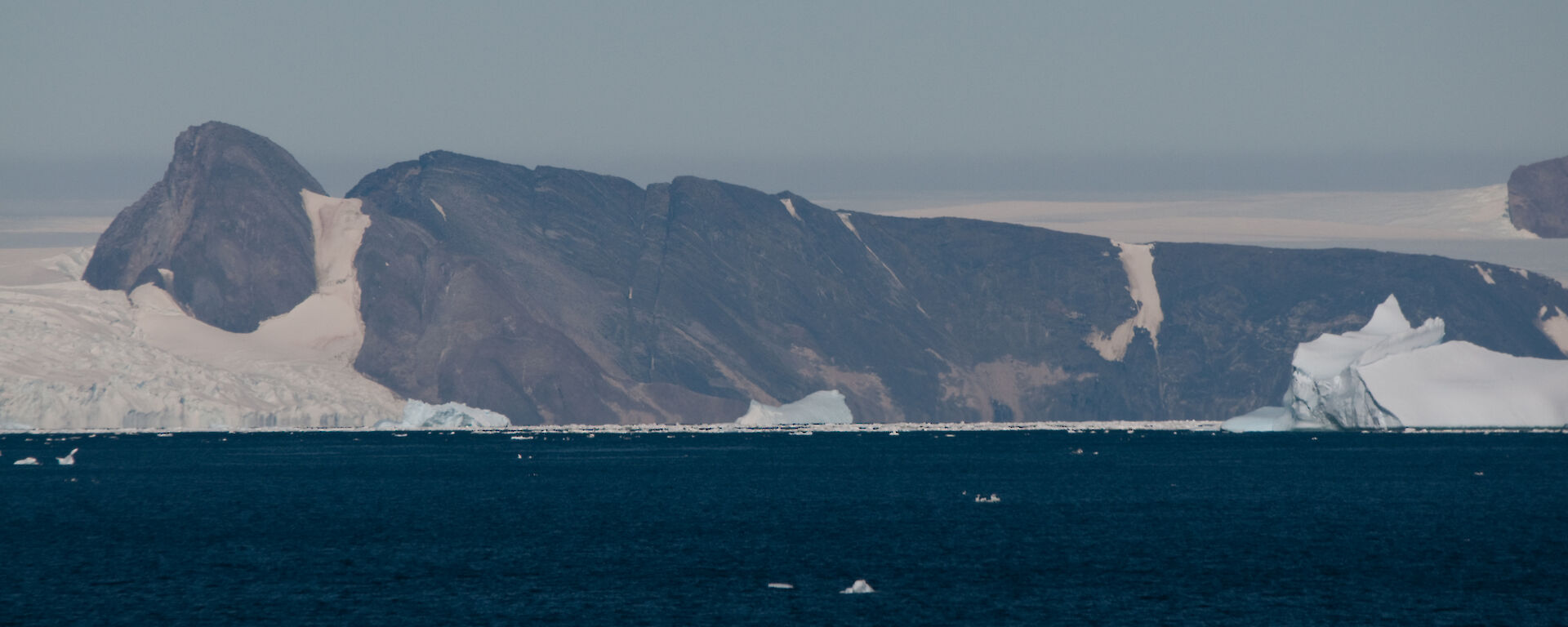 An aerial view from the water of a large monolith covered in ice