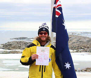 Man holding a piece of paper in front of the Australian flag