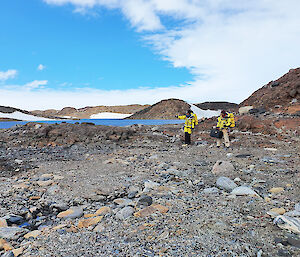 Two scientists on the rocky shores of a lake