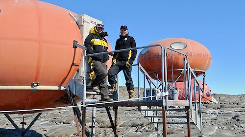 Two scientists standing in front of a field hut