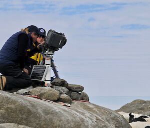 A man and a woman sitting next to a camera on a tripod