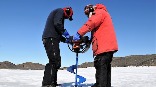 two men with large auger on sea ice