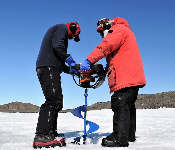 two men with large auger on sea ice